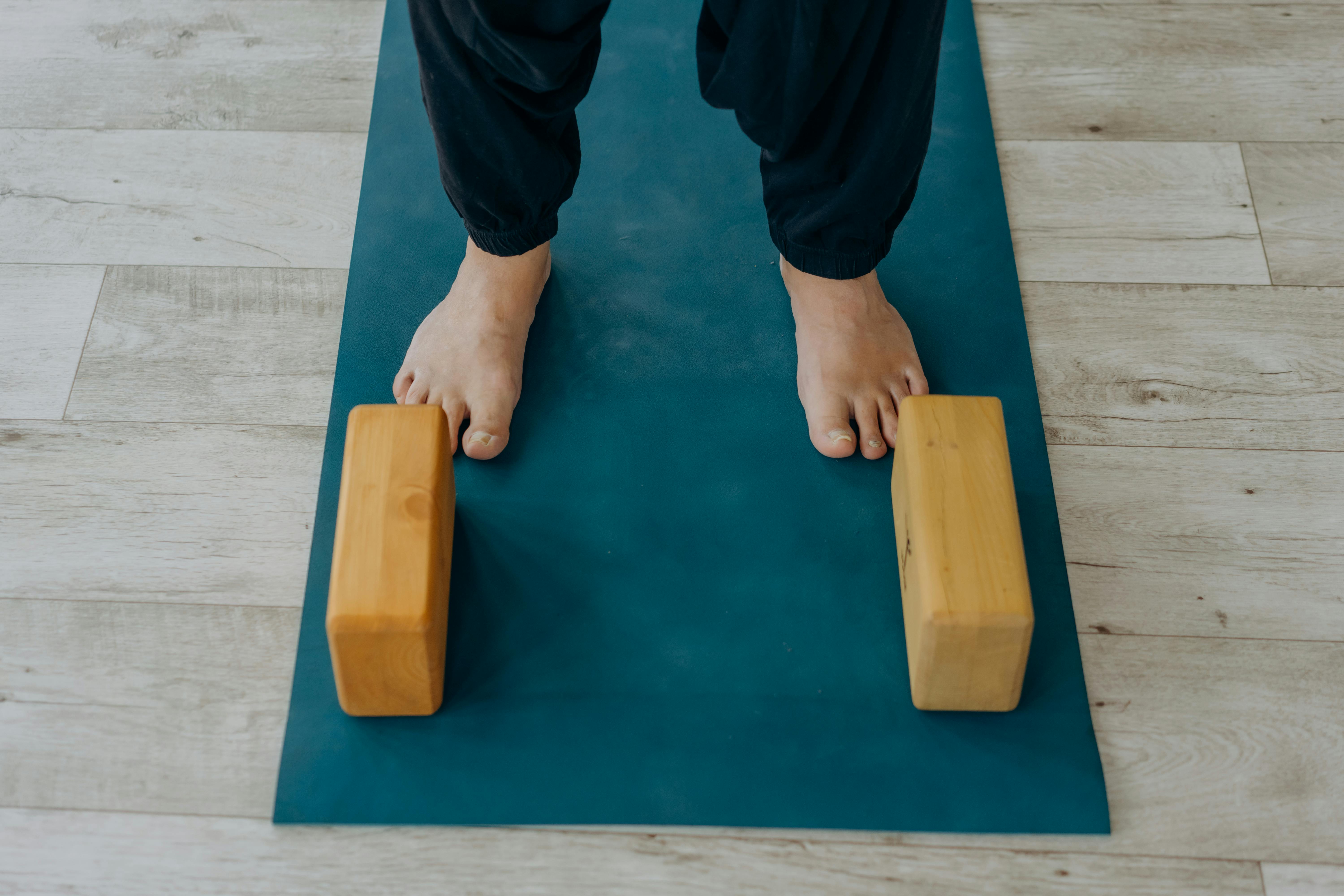 Two sets of feets on a yoga mat with blocks on each side of the feet.