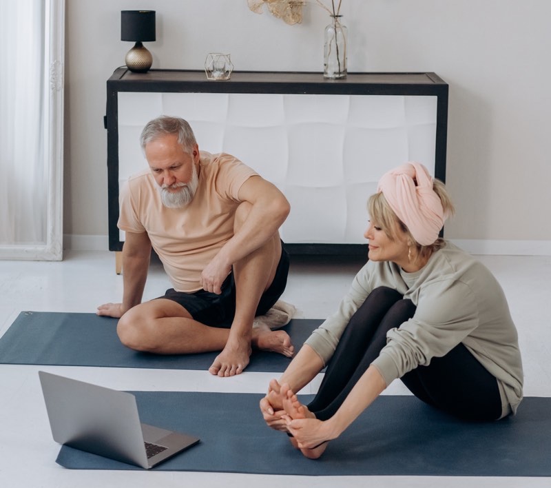 Seniors couple doing yoga at home.