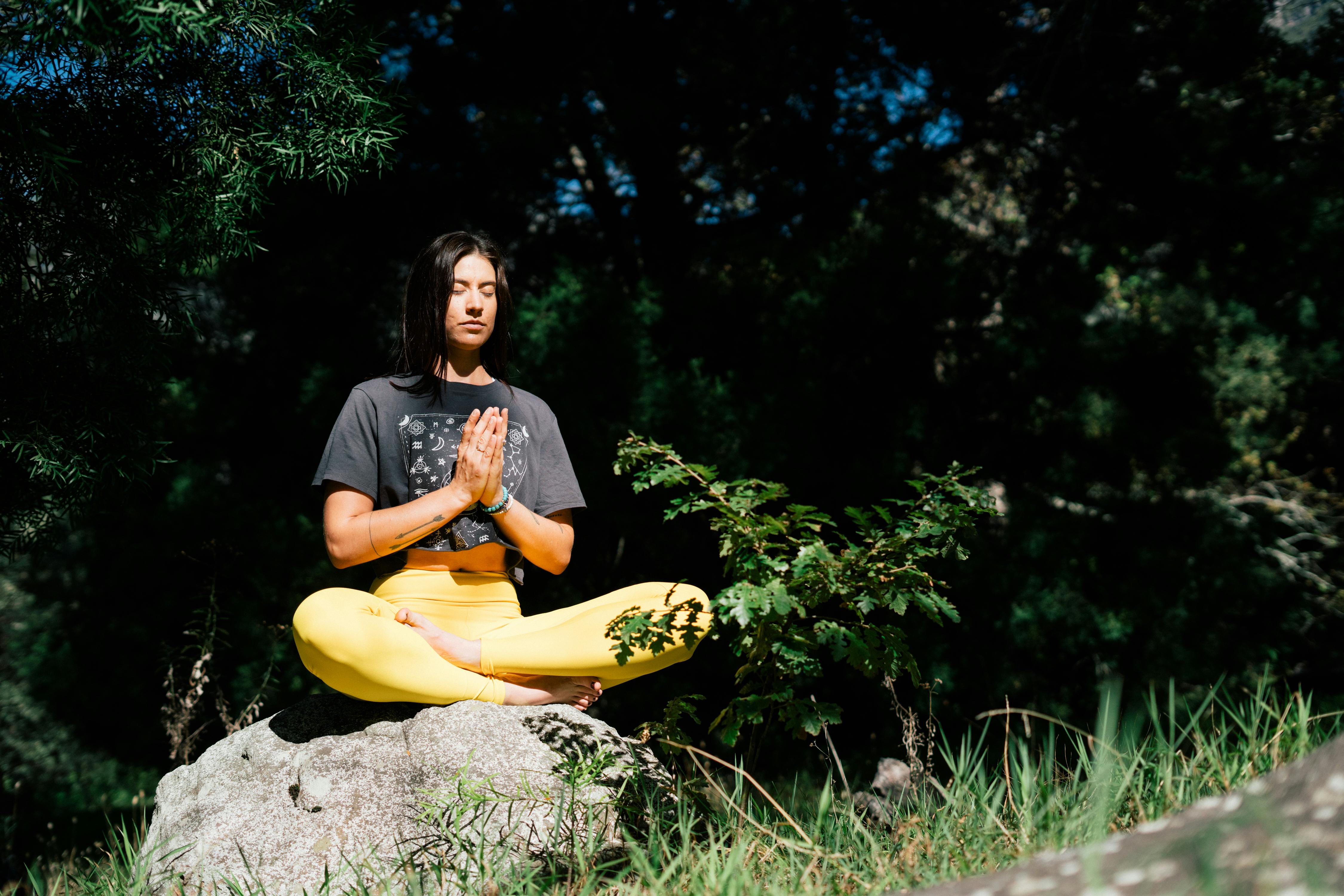 yogi meditating on a  small boulder